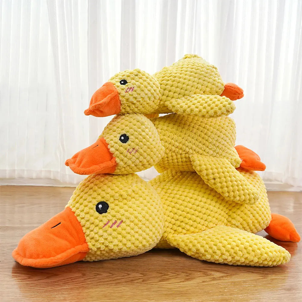 Three yellow duck plush toys with orange beaks on a wooden floor.