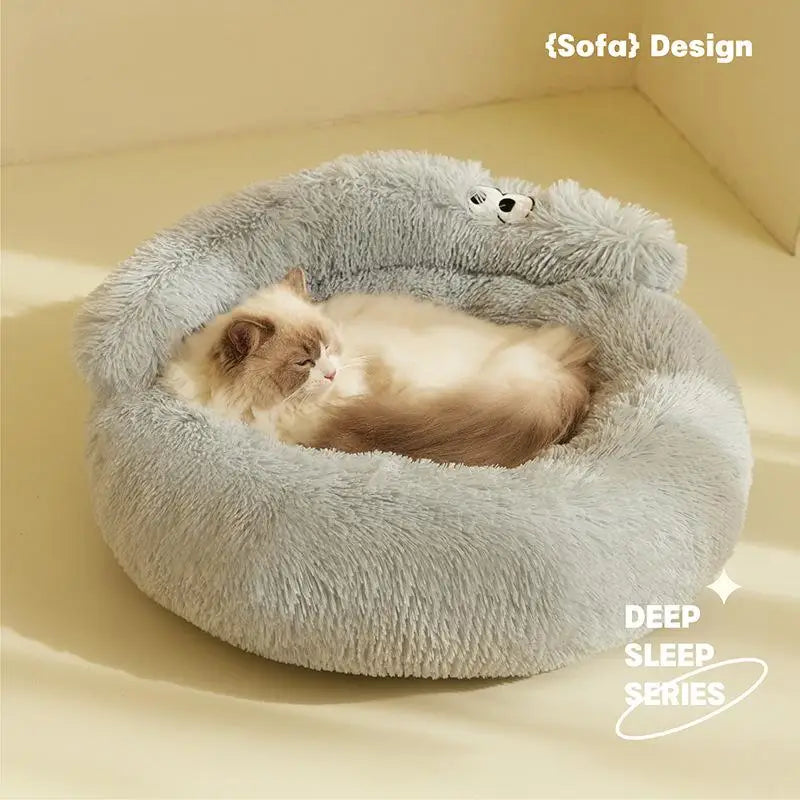 Cat lying on a fluffy gray pet bed with a teddy bear toy on a beige background