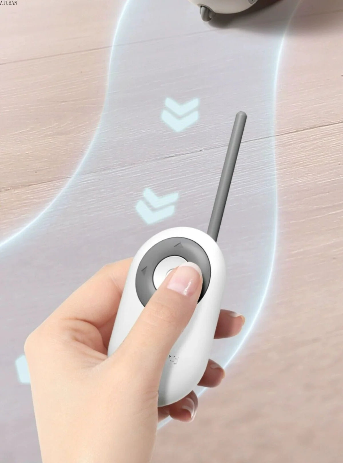 Hand holding a white electronic device with a gray arrow on a light wooden surface.