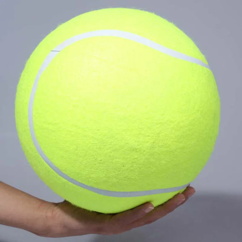 Large yellow tennis ball held by a hand against a gray background