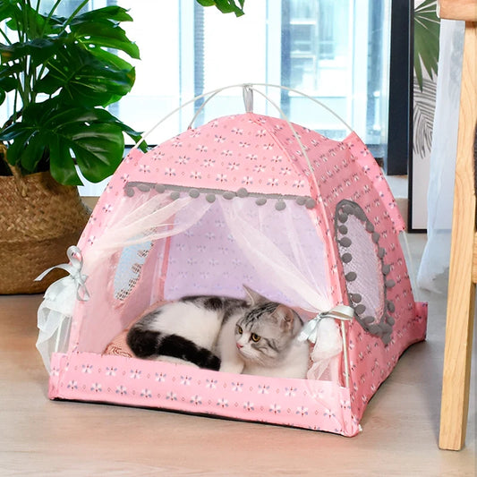 Pink pet tent with a cat inside, placed on a wooden floor with a plant in the background.